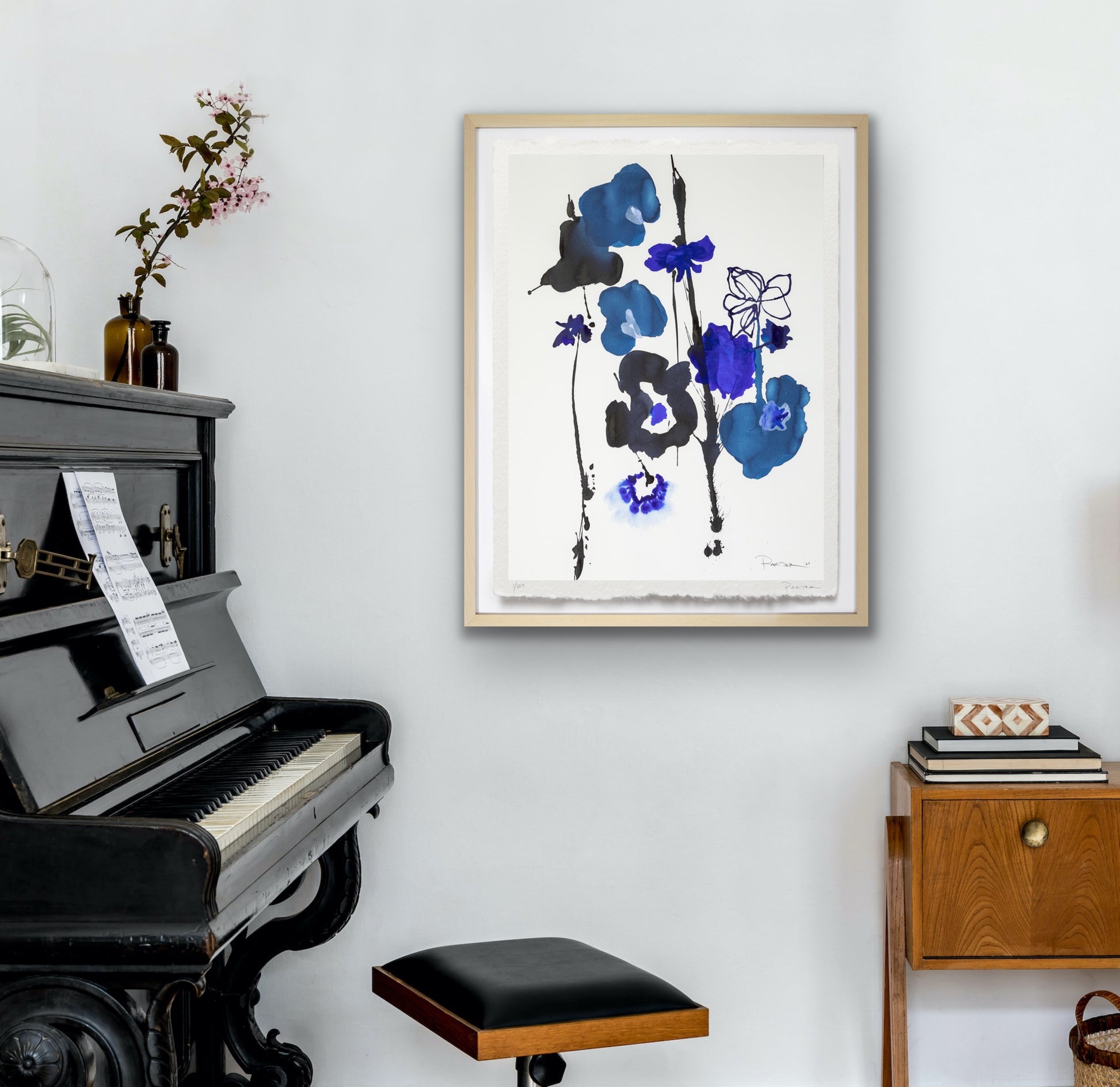 Framed floral abstract art above a piano in a room with a wooden side table.