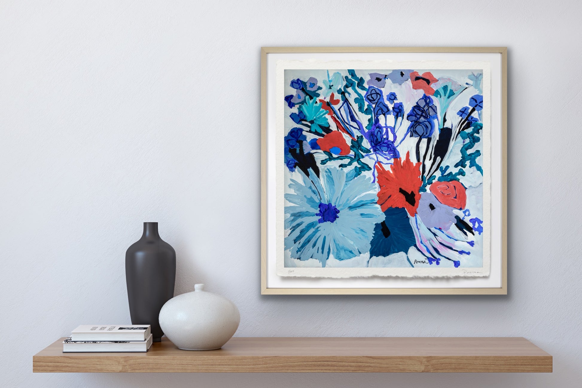 Framed colorful botanical abstract artwork with flowers on a wooden shelf against a white wall