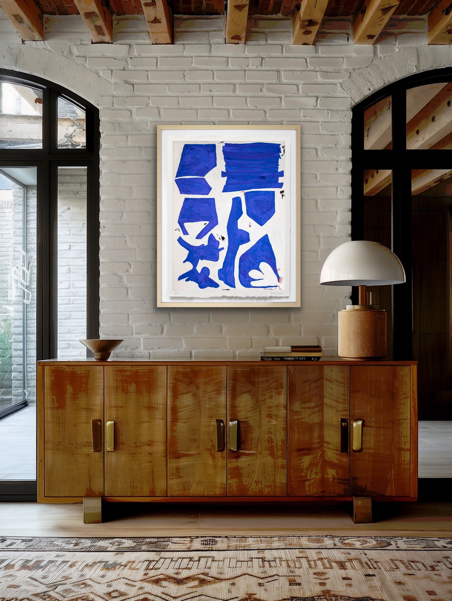 Warm industrial accents with blue and white abstract geometric artwork displayed in entryway.