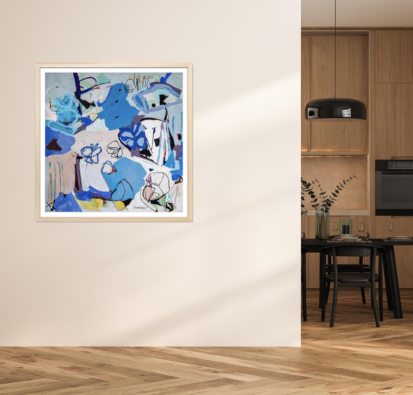 Abstract painting in a wooden frame on a wall in a room with a kitchen.